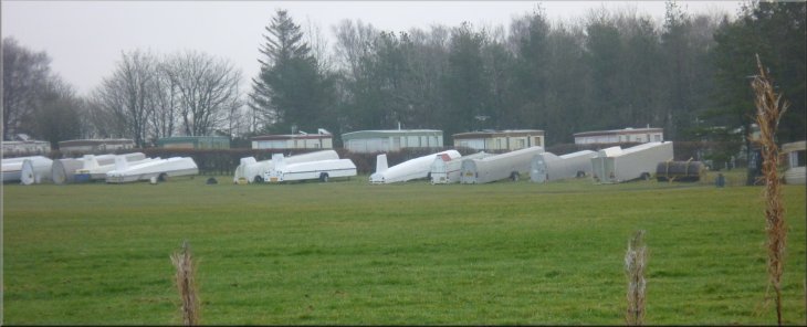 Gliders in their cases lined up by the glider club caravan park