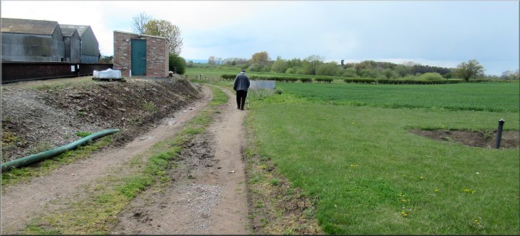 Following the public footpath between the farm buildings and the grassland in front of the brick house