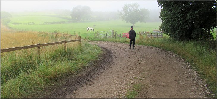 Farm track turning left towards some more farm buildings, morning mist still persisting